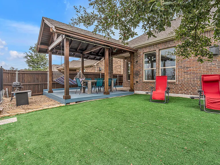 Ground-level covered deck with a fire table, a gas grill, dining for 6, and a hammock. Adjustable roll-down shades.