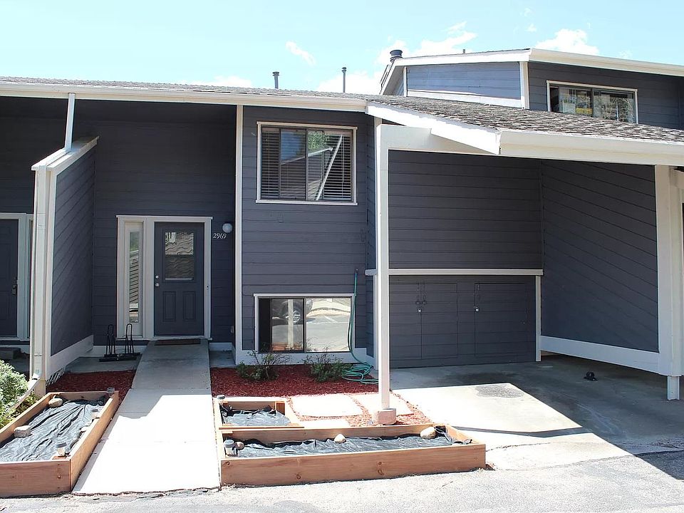 Front of townhouse with covered parking spot, storage and garden beds
