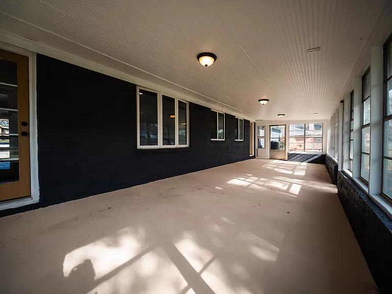 Sun-filled enclosed porch with panoramic windows overlooking the yard