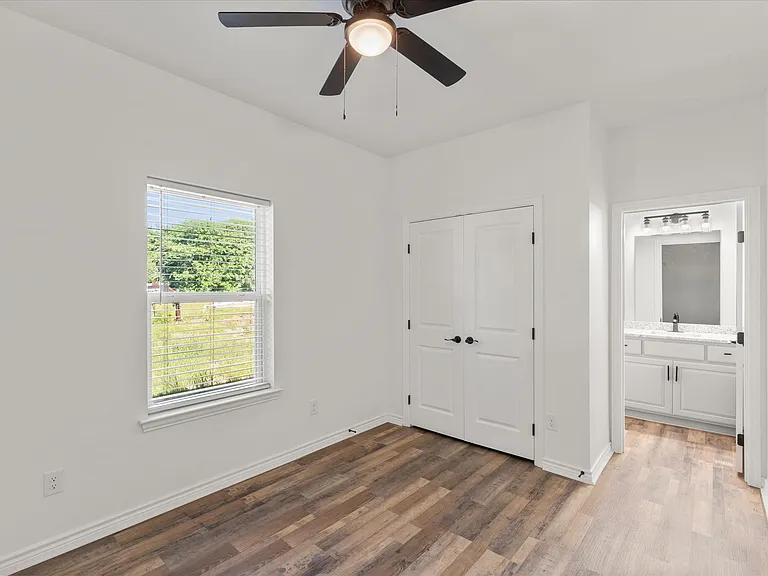 Room featuring wood-finish flooring, a ceiling fan, and a window with blinds