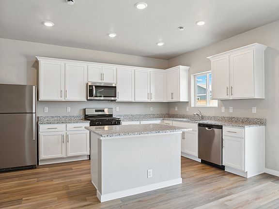 The kitchen has stainless steel appliances and plank flooring.
