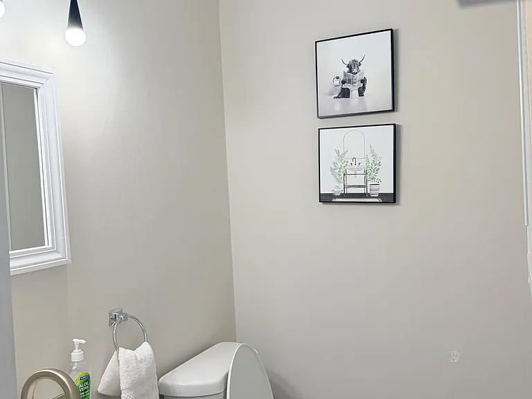 Half bath featuring a vanity sink, toilet, wall art, and a window for natural light.