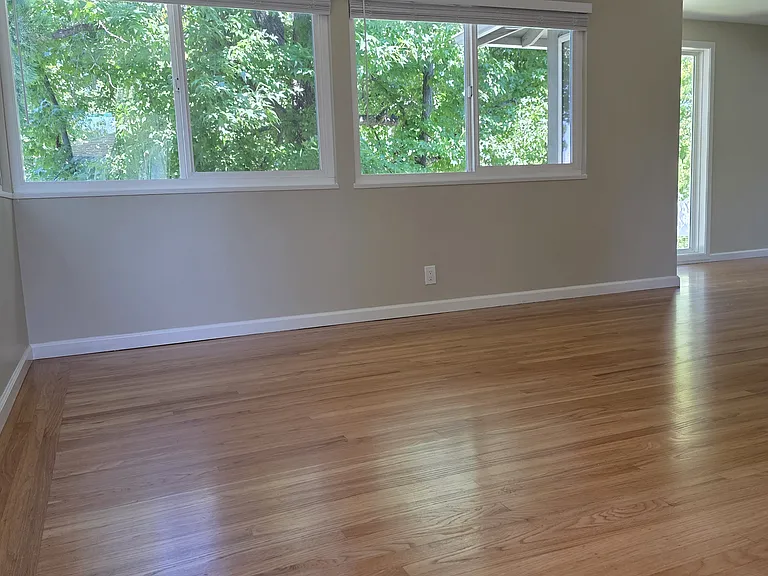 Large living room with hardwood floors and dual pane windows. View from farthest corner from front door.