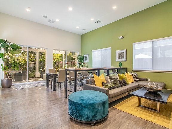 Club Room with hardwood style flooring, high ceilings, sofa, and dining seating.