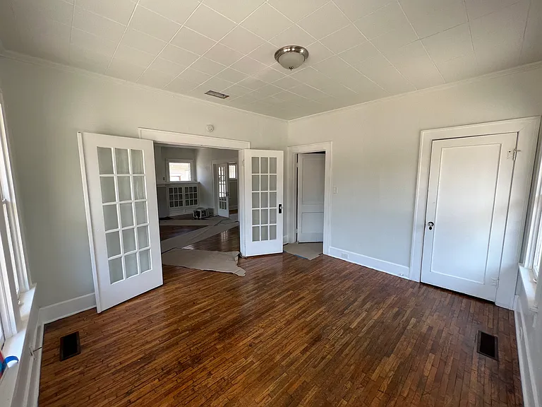 Front bedroom looking northeast toward hallway door leading to bath and other bedrooms and French doors leading to the Living Room and front entrance.