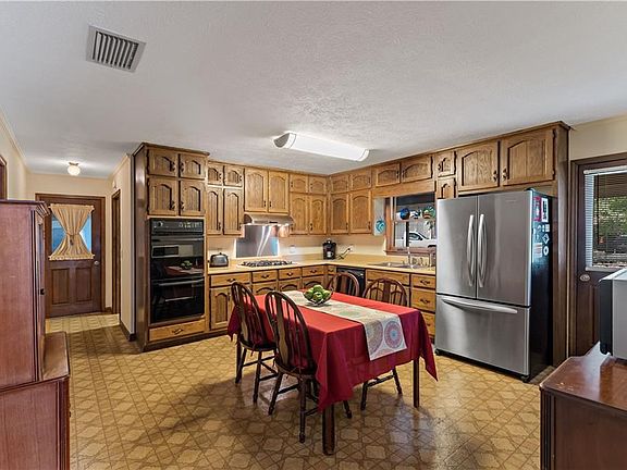 Spacious kitchen with double wall ovens, gas cooktop, dishwasher, vent hood and pantry, side door access to covered porch and rear yard