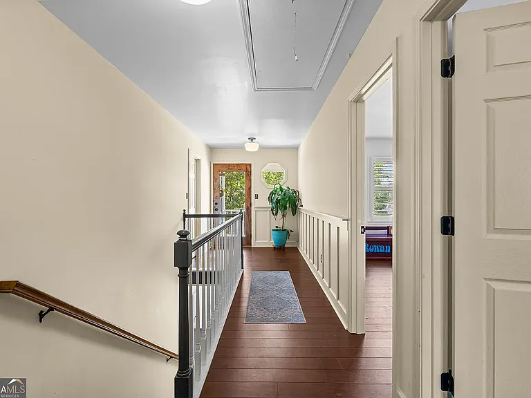 Second floor hallway with access to 3 bedrooms, one full bathroom, and second floor balcony. Board and batten accents.