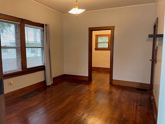 standing at front door looking into tv room and office. There are a total of 3 windows in the tv room. Has a center ceiling light, no fan.