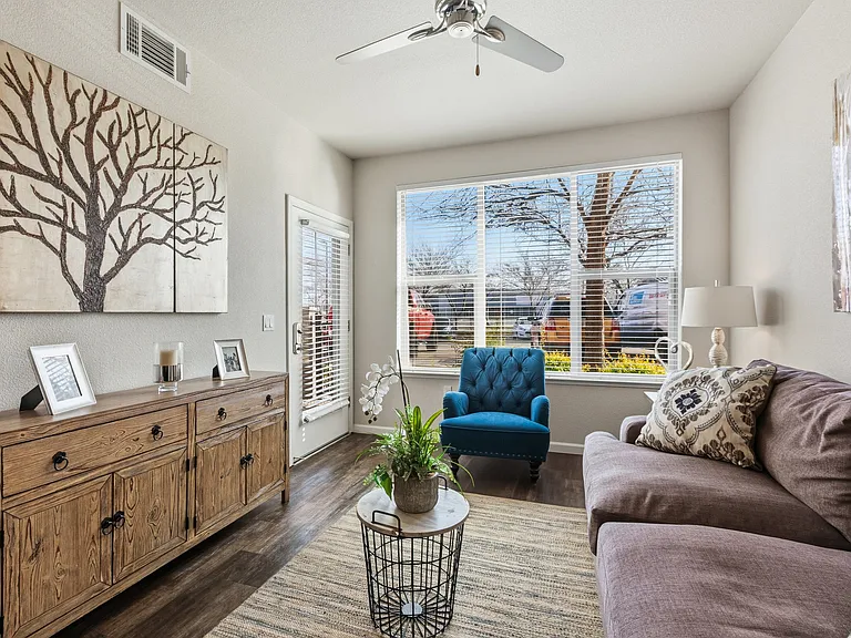Aspire Apartments Tracy CA A living room with a blue chair and a painting of a tree on the wall.