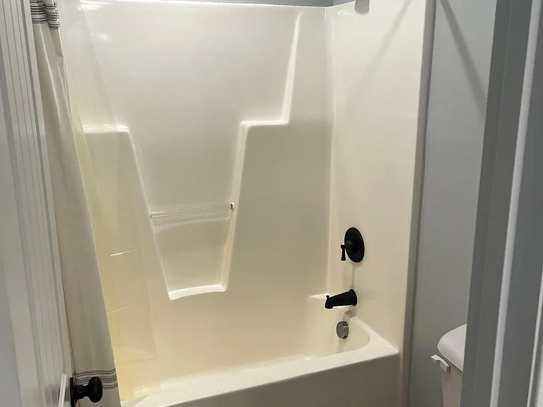 Full guest bathroom with tub-and-shower combination, and built-in shelving.