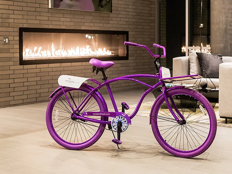 Resident lounge at night with fireplace lit and a Modera bicycle in center