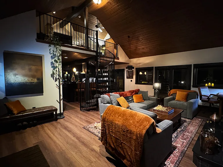 Open-concept living room viewed from the loft, highlighting dramatic ceilings and architectural design.