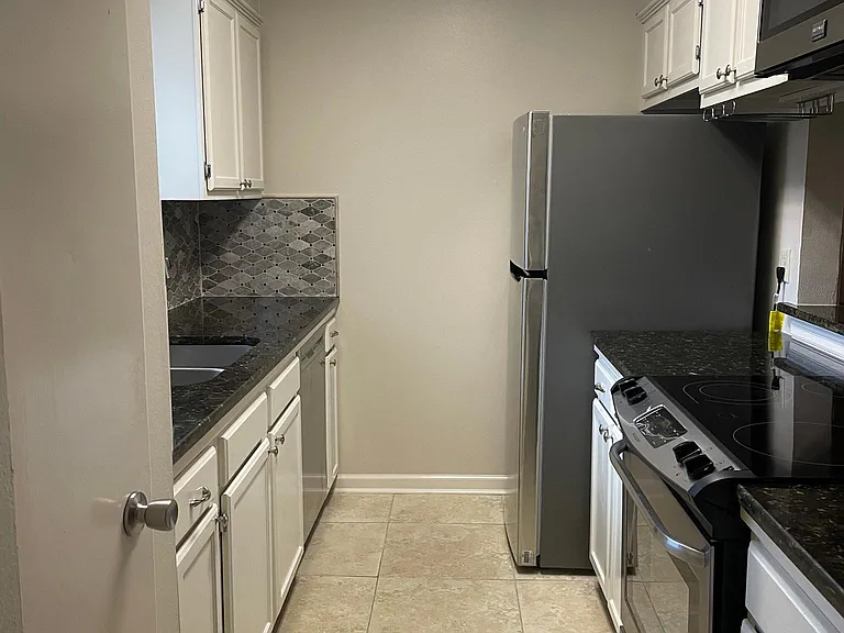galley kitchen with stove, refrigerator and dishwasher with marble countertops and pantry