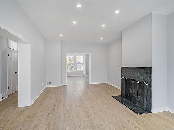 Main level: living room with a real fire place framed by green marble. Looks into the formal dining room that can also be used as a home office or an additional living space