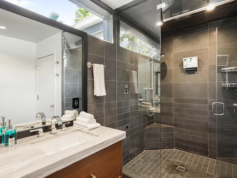 Step into the expansive walk-in glass shower, offering ample space and modern elegance.