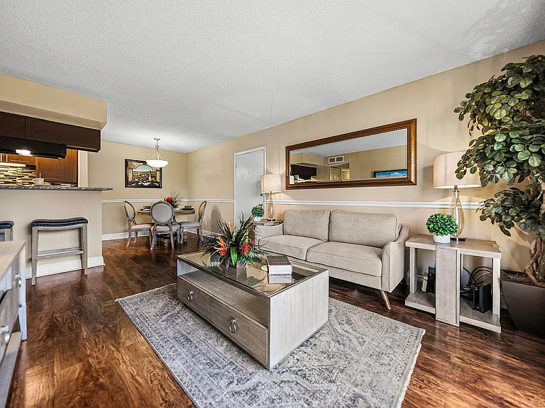 Bright and spacious living and dining area with wood-style flooring and an open layout connecting to the kitchen.