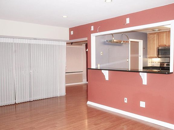 Living room with view of kitchen and dining room. Wall to wall balcony access door