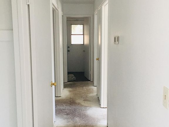 Hallway to the right of living room with laundry room at the end of the hallway.