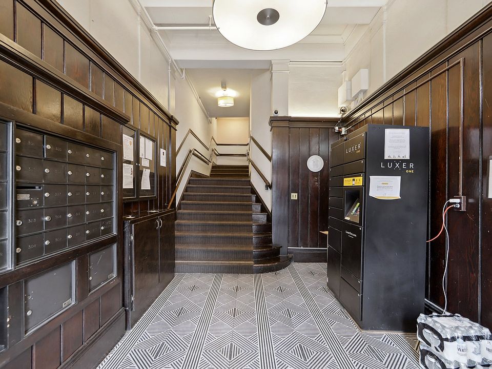 Entrance hall featuring wooden paneling, mailboxes, staircase, and a Luxer package locker against a patterned floor