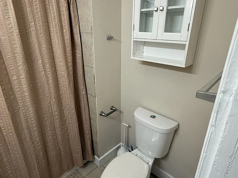Full bathroom with a tiled tub/shower surround, and toilet.