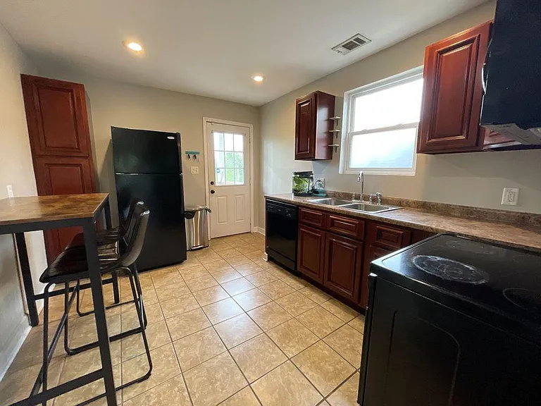 Full kitchen with island seating, dishwasher, full-size appliances, and back porch access.