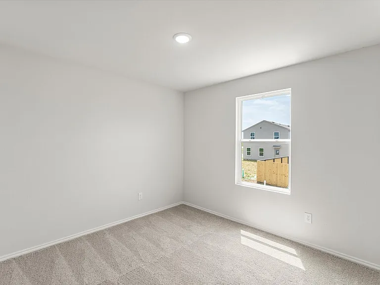 Bright interior space featuring light gray walls, plush carpet flooring, a single window, recessed lighting, and white trim throughout