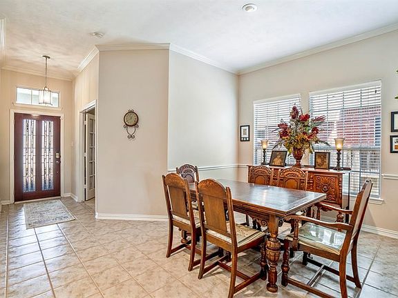 The dining room area has a large window that streams in natural light and neutral paint tones with crown moldings and chair rail molding.