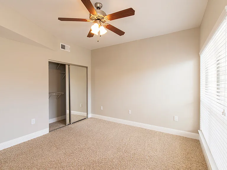Spacious bedroom with ceiling fan and large window