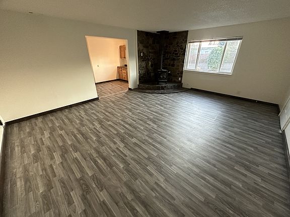 Large family room with wood burning stove. New vinyl flooring and wood baseboard.