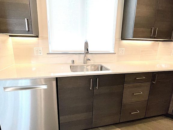Kitchen with sink and dishwasher, under cabinet lighting, screen over window