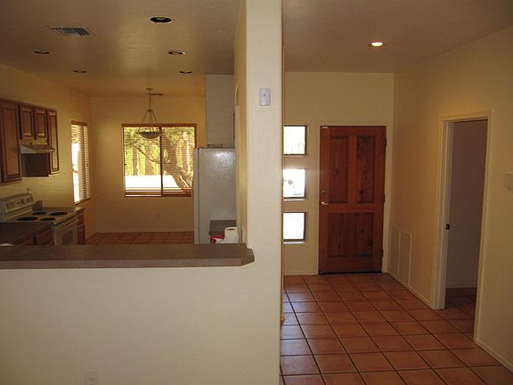 Breakfast bar looking into eat-in kitchen with canned lighting, laundry room to right & front door