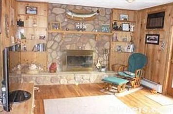 Den with wood burning stone fireplace