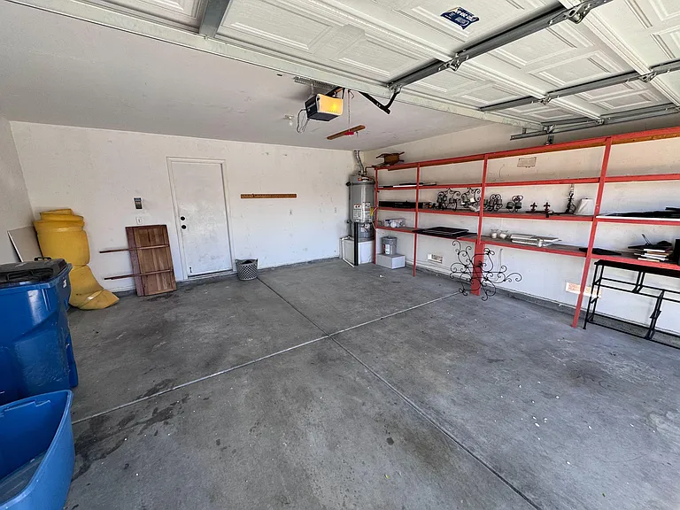 Attached garage with concrete flooring, built-in shelving, and space for storage, tools, or parking.