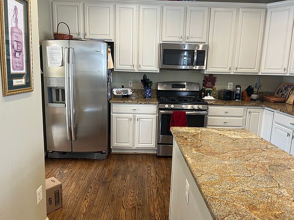 Beautiful stainless steel kitchen with newer hardwood floors, granite counters, and white cabinets.