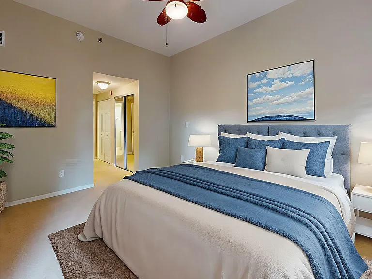 Inviting bedroom featuring elegant decor with a plush bed, calming blue accents, modern lamp, vibrant artwork, and lush greenery for a serene ambiance.
