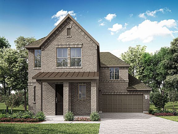 A two-story brick house with a gabled roof, surrounded by lush greenery and a clear blue sky with fl