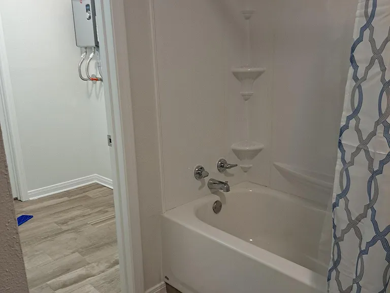 Brand new tub and enclosure next to laundry room with new on demand water heater