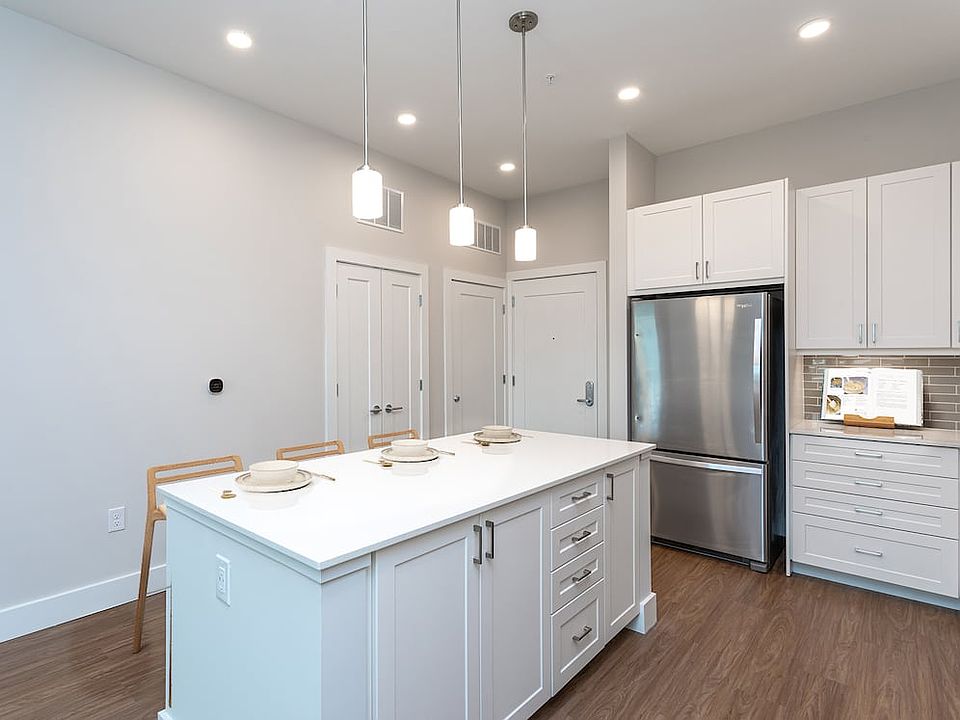 Modern kitchen with white cabinetry, undercabinet lighting, grey tile backsplash, and white quartz countertops