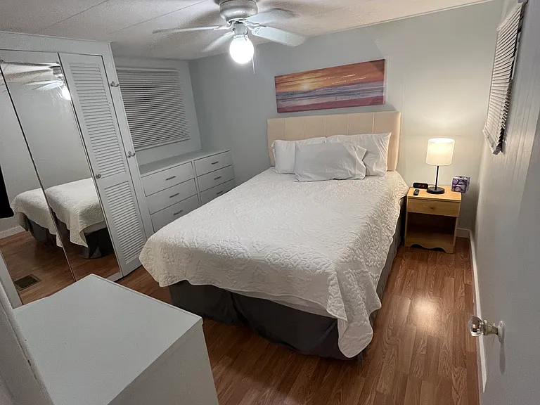 The primary bedroom with lots of built-in storage, a queen bed and a double reach-in mirrored closet.