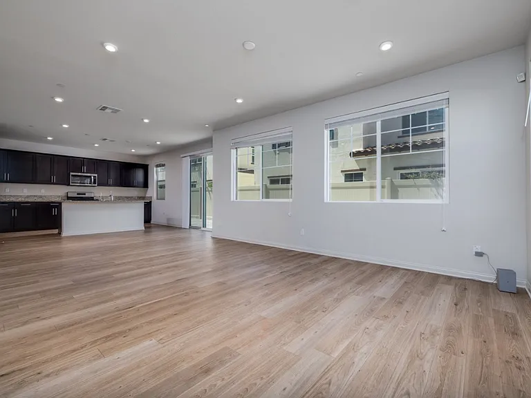 Another view of the spacious living area featuring laminate flooring, recessed lighting, and large windows facing the backyard_creating a bright, open space ideal for family gatherings and entertaining.