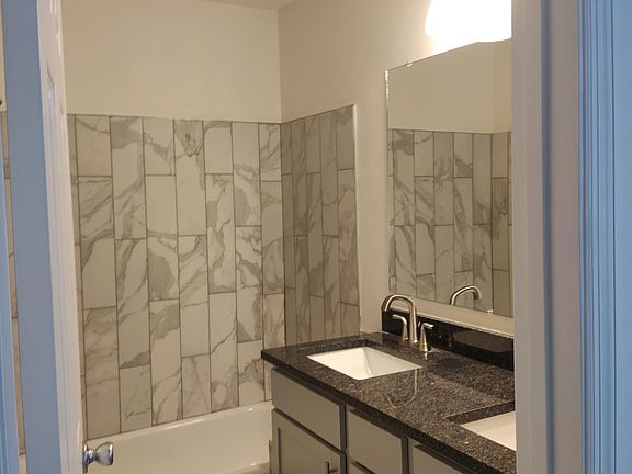 Double vanities, new granite, new tile flooring and tub surround. Toilet is just behind the door.
