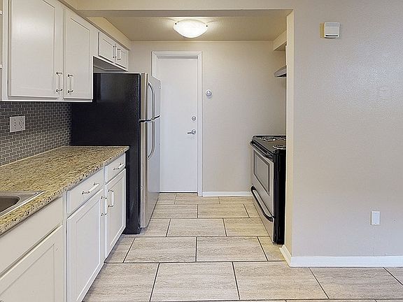 Sleek kitchen with modern appliances, granite countertops, and elegant cabinetry in a cozy apartment unit.