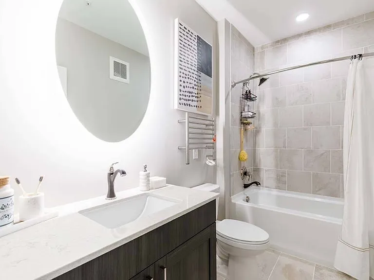 Spa-inspired bathrooms with round backlit bathroom mirrors and heated towel racks*