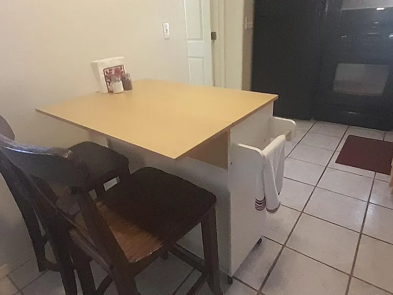 Bar height dining table with bar stools. Appliances, sink and counter.