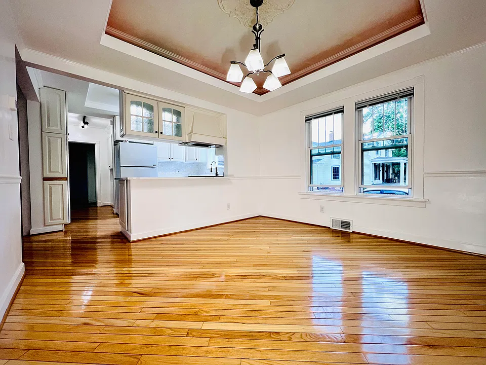 Adjacent to the kitchen, the spacious main dining room features rich hardwood floors and abundant natural light from large windows_creating an ideal, open space for everyday meals and entertaining.