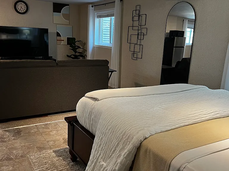 Comfortable queen bed with cozy lighting and nearby workspace for extended stays.