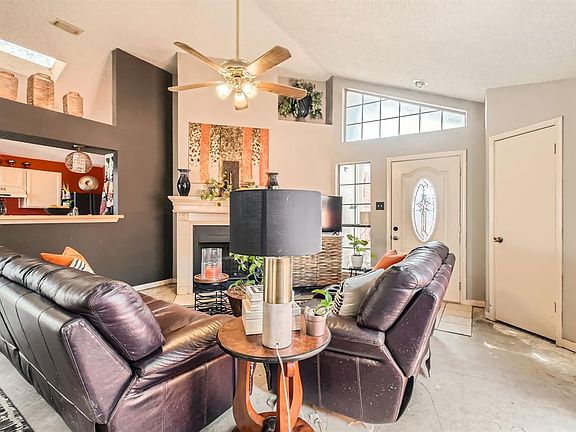 Living area with high vaulted ceiling, a fireplace, baseboards, and a ceiling fan