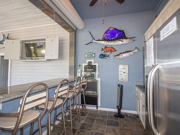 Outdoor kitchen with wine fridge, ice maker, two stove top burner, sink, refrigerator and upgraded sound system. Three TV's