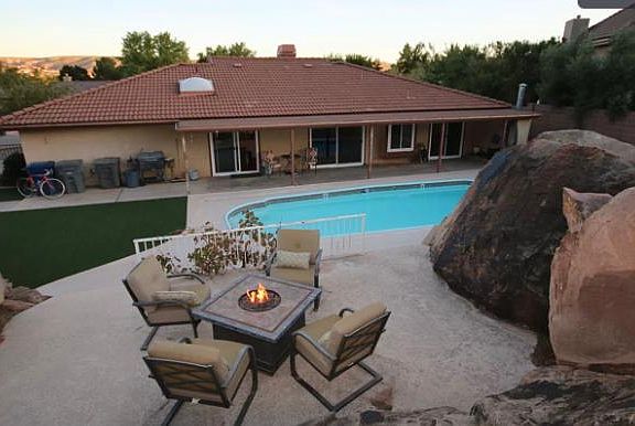Large backyard with pool and separate area for fire pit. Covered patio for lounging.