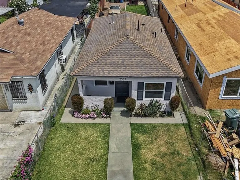 Aerial view of a single-story home with a fenced front yard, paved walkway, and low-maintenance landscaping.